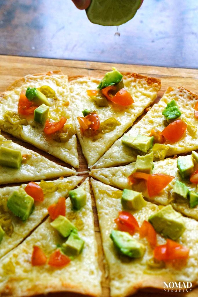 Cheese crisp with avocado, tomatoes, and green chilies (adding lime juice to it)