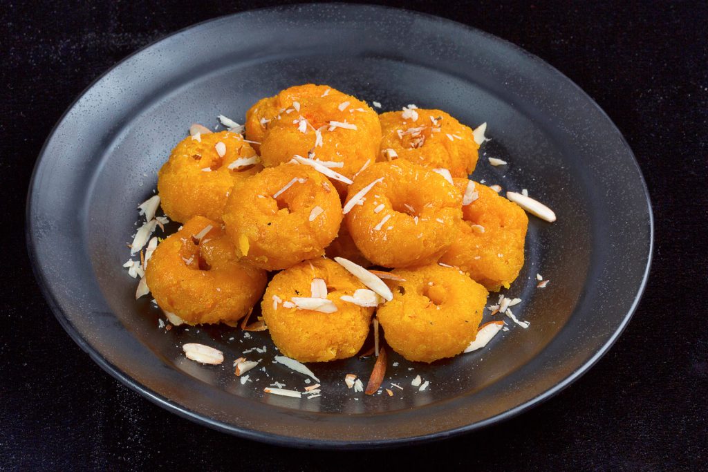 Flaky, sweet doughnuts called Badusha, topped with coconut flakes.
