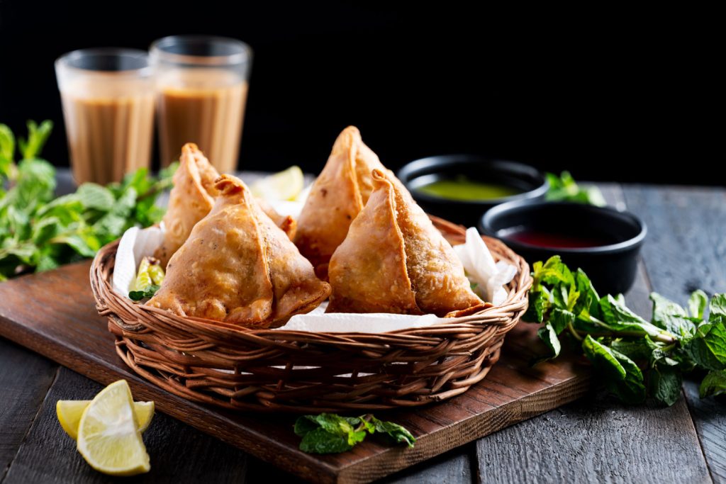 Samosas with chutney and tea in the background.