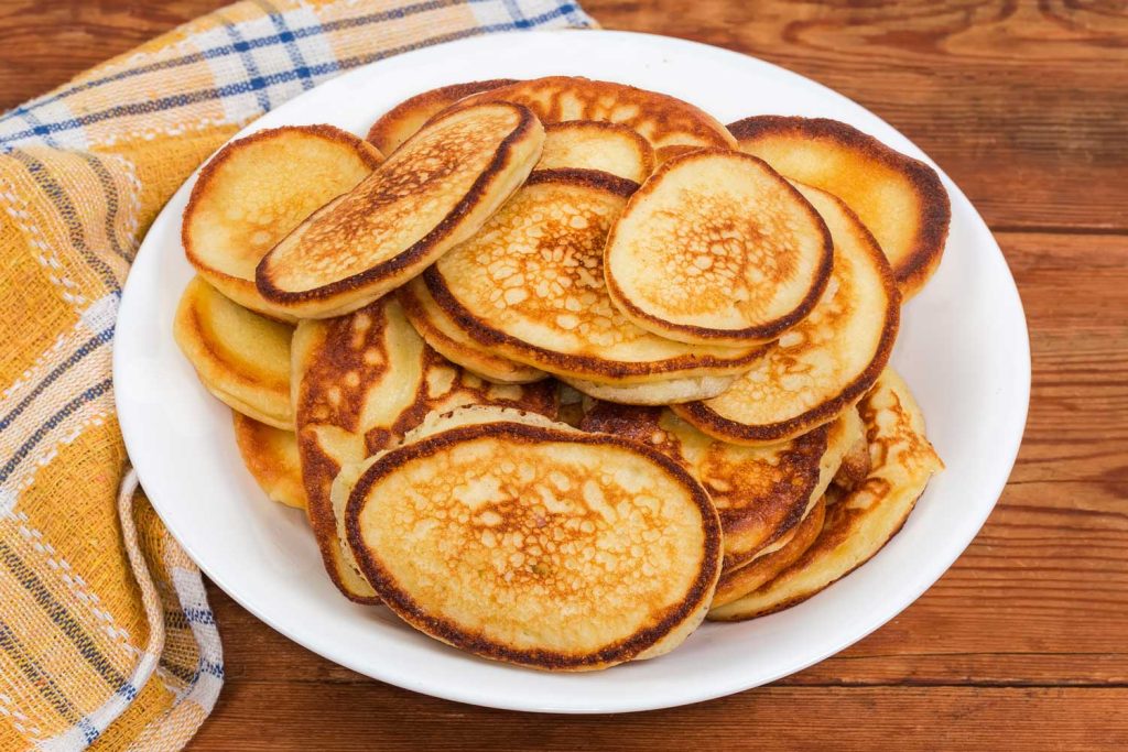 Oladky (Оладки) – Kefir Pancakes served in a pile on a plate.